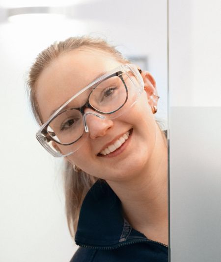 Lächelnde Mitarbeiterin des Zahnzentrums Deichkrone schaut um die Ecke